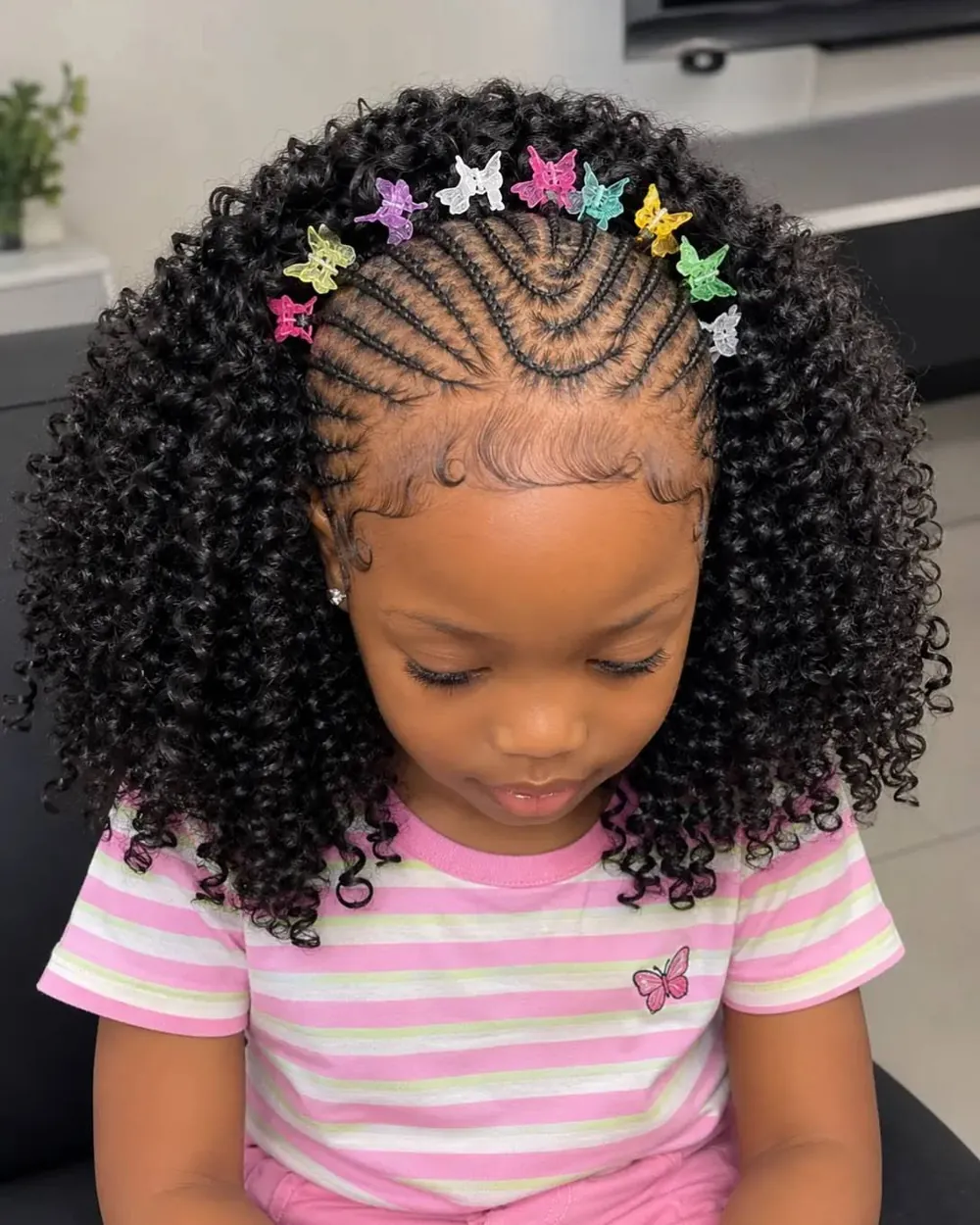 Little girl with cornrows into curls and butterfly clips